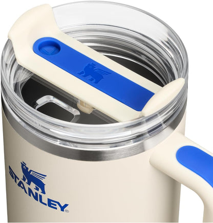 Beige Stanley mug with blue handle and lid on a white background