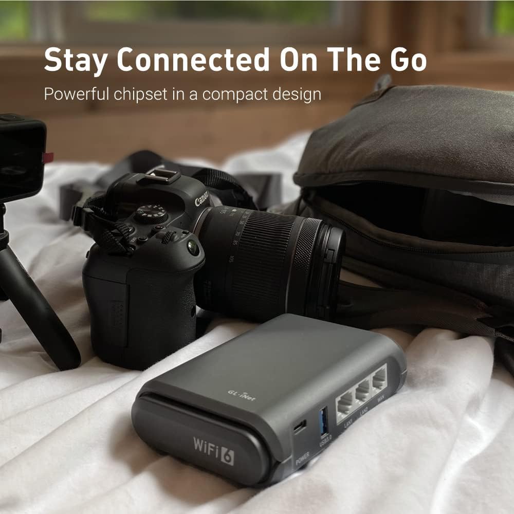 GL.iNet Slate AX travel router displayed in a compact travel setup with a camera on a bed showing text Stay Connected On The Go