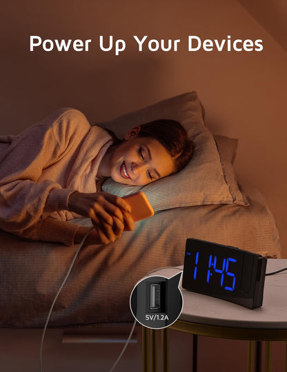 GOLOZA projection alarm clock displaying 'Power Up Your Devices' with a smartphone charging via the built-in USB port next to a person sleeping in bed.