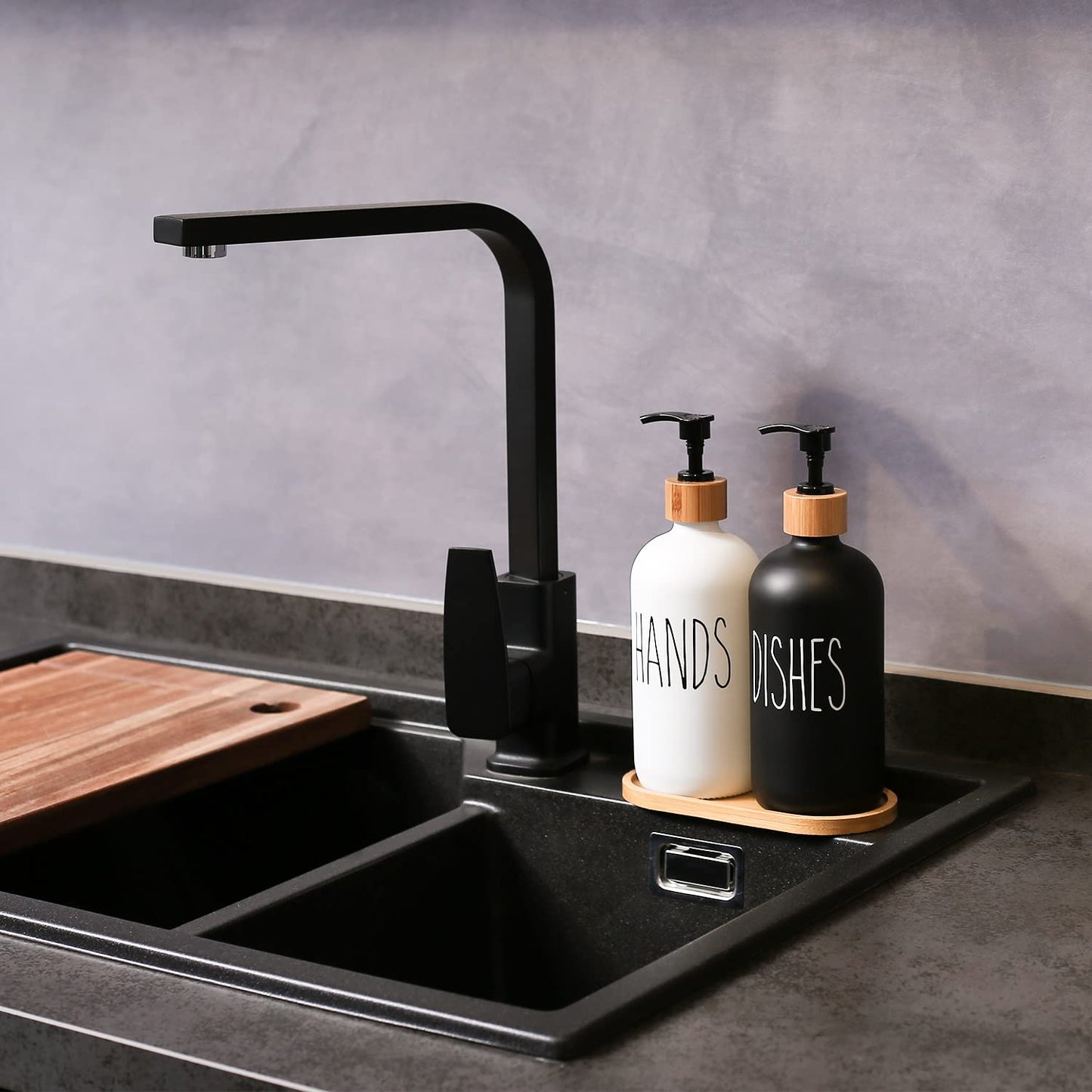 Modern kitchen sink with black faucet and cleaning supplies on a gray countertop.
