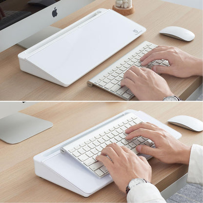 Person using a keyboard on a wooden desk with a computer monitor and mouse.