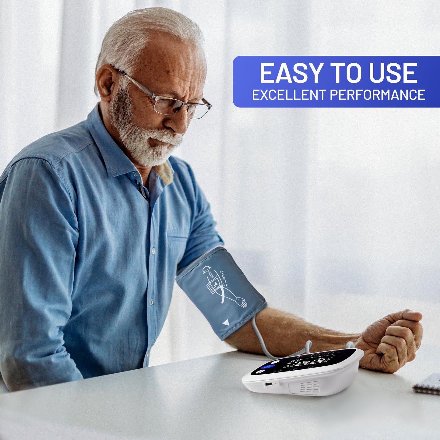 Older man sitting at a table using the REDIVN upper arm blood pressure monitor, with text overlay reading 'Easy to use, excellent performance'.